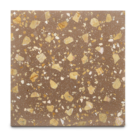 The Jacinto 24x24 by Zia Tile is a handmade square tile with a brown base and terrazzo pattern featuring yellow, beige, and white fragments, shown beautifully on a white surface.