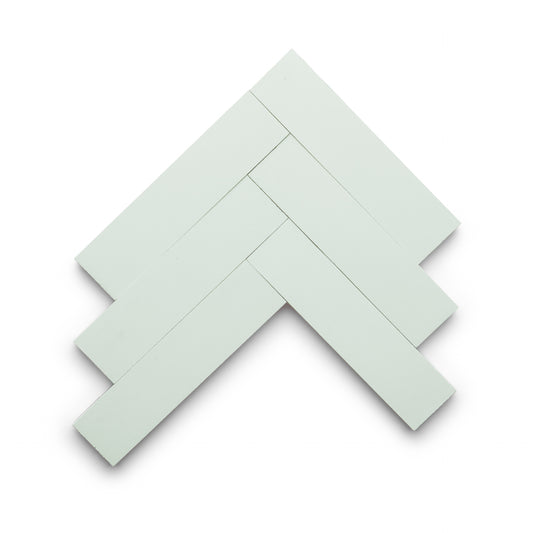 Six Julep 2x8 rectangular white tiles from Zia Tile are arranged in a herringbone pattern on a white background.