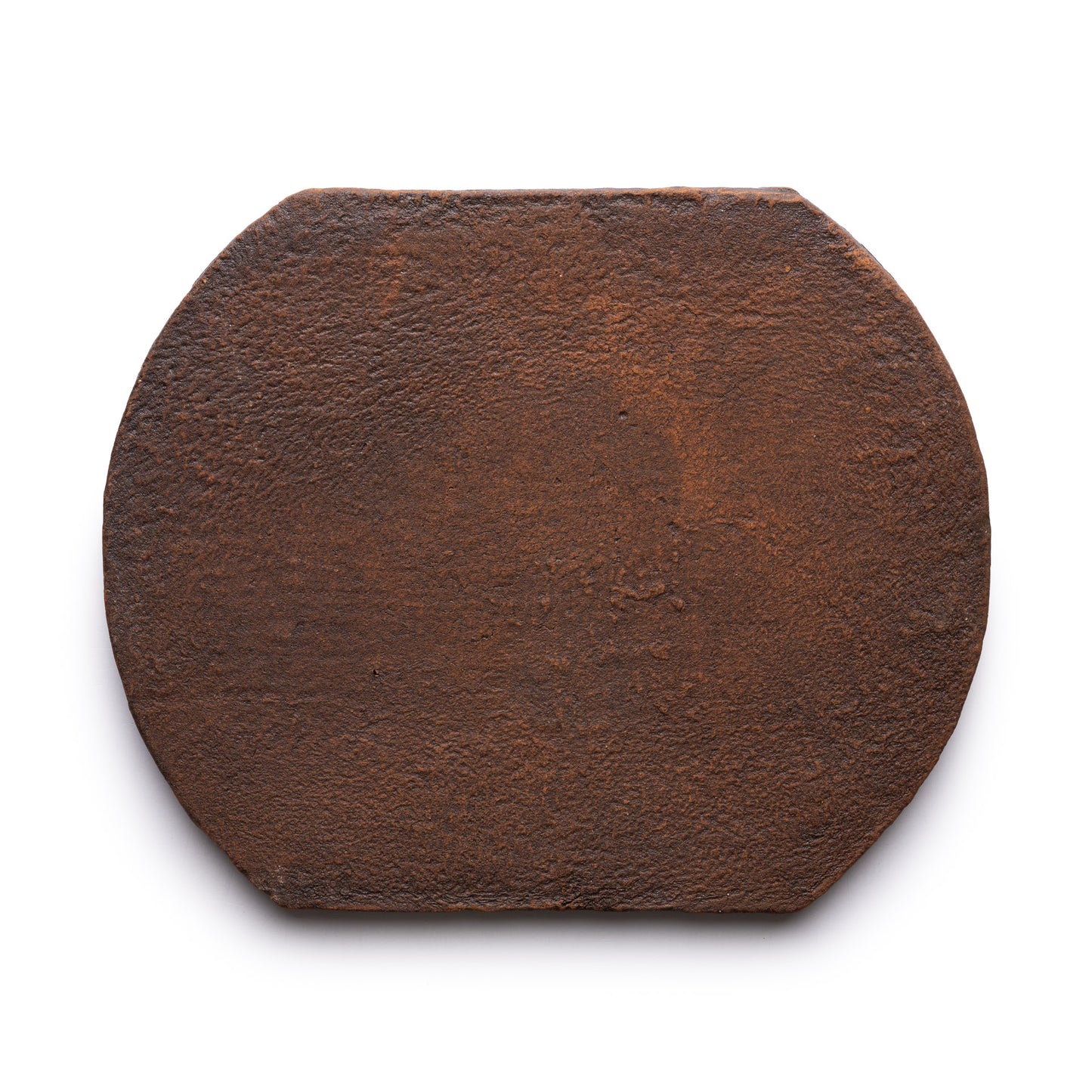 The Oaxaca + Madera tile by Zia Tile is a round, flat, dark brown tile with slightly angled edges and a rustic texture, resembling a compressed disk of tea, shown against a white background.