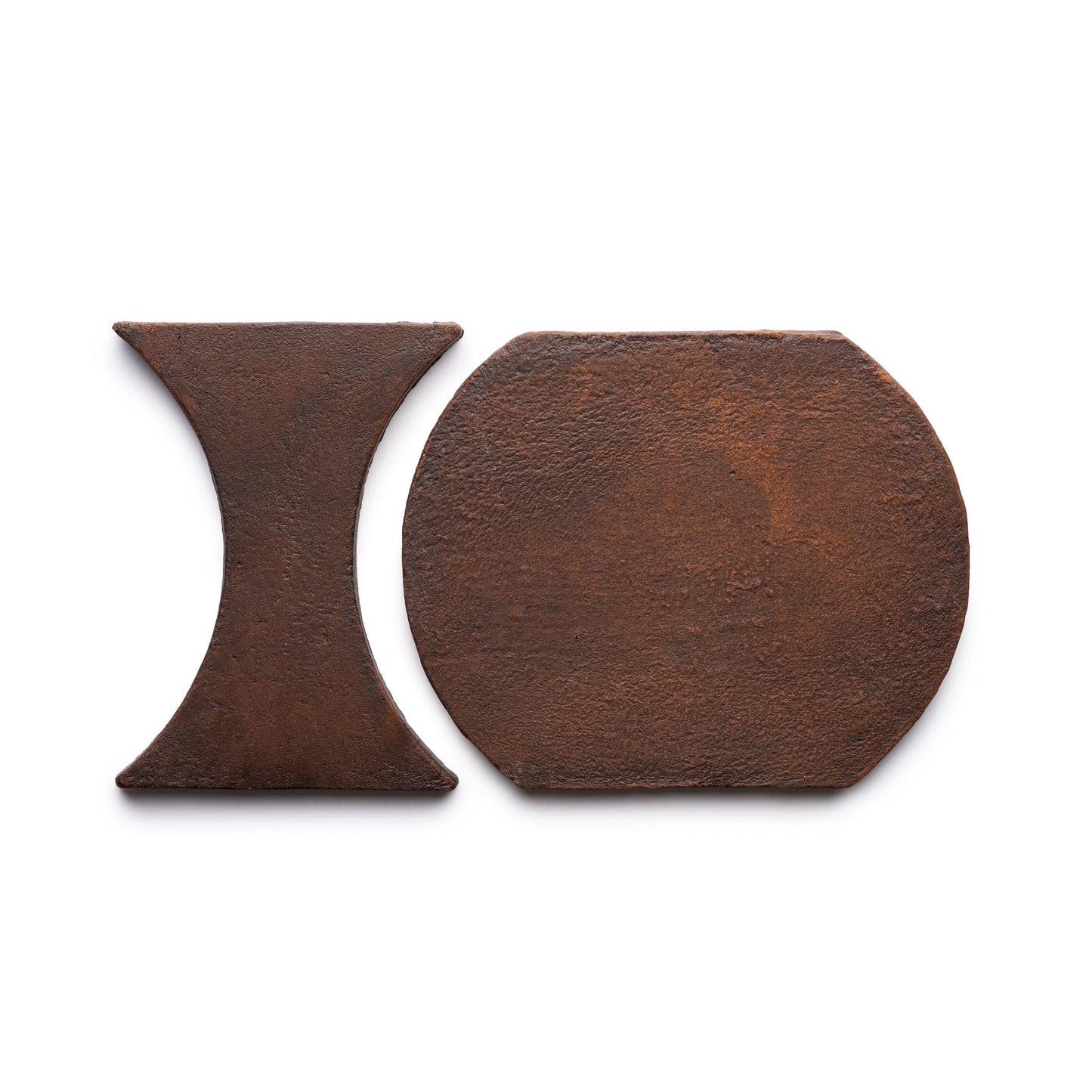 Two rusty metal pieces, Oaxaca + Madera by Zia Tile, are shown on a white background: one is hourglass-shaped and the other has a rounded rectangle shape.