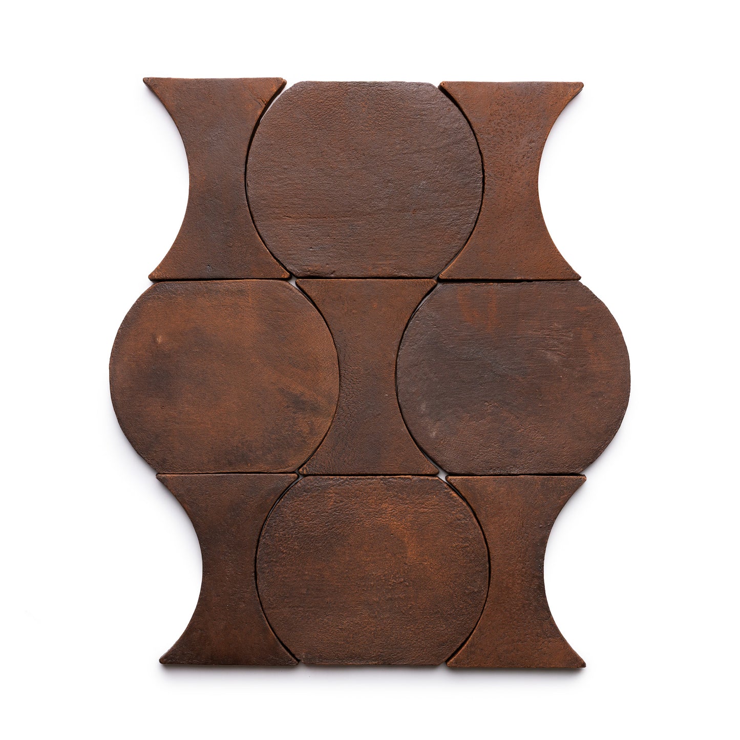The Oaxaca + Madera tiles by Zia Tile feature six rust-colored, dark brown tiles with curved, circular edges arranged in a symmetrical geometric pattern on a white background.