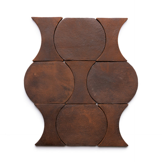 The Oaxaca + Madera tiles by Zia Tile feature six rust-colored, dark brown tiles with curved, circular edges arranged in a symmetrical geometric pattern on a white background.