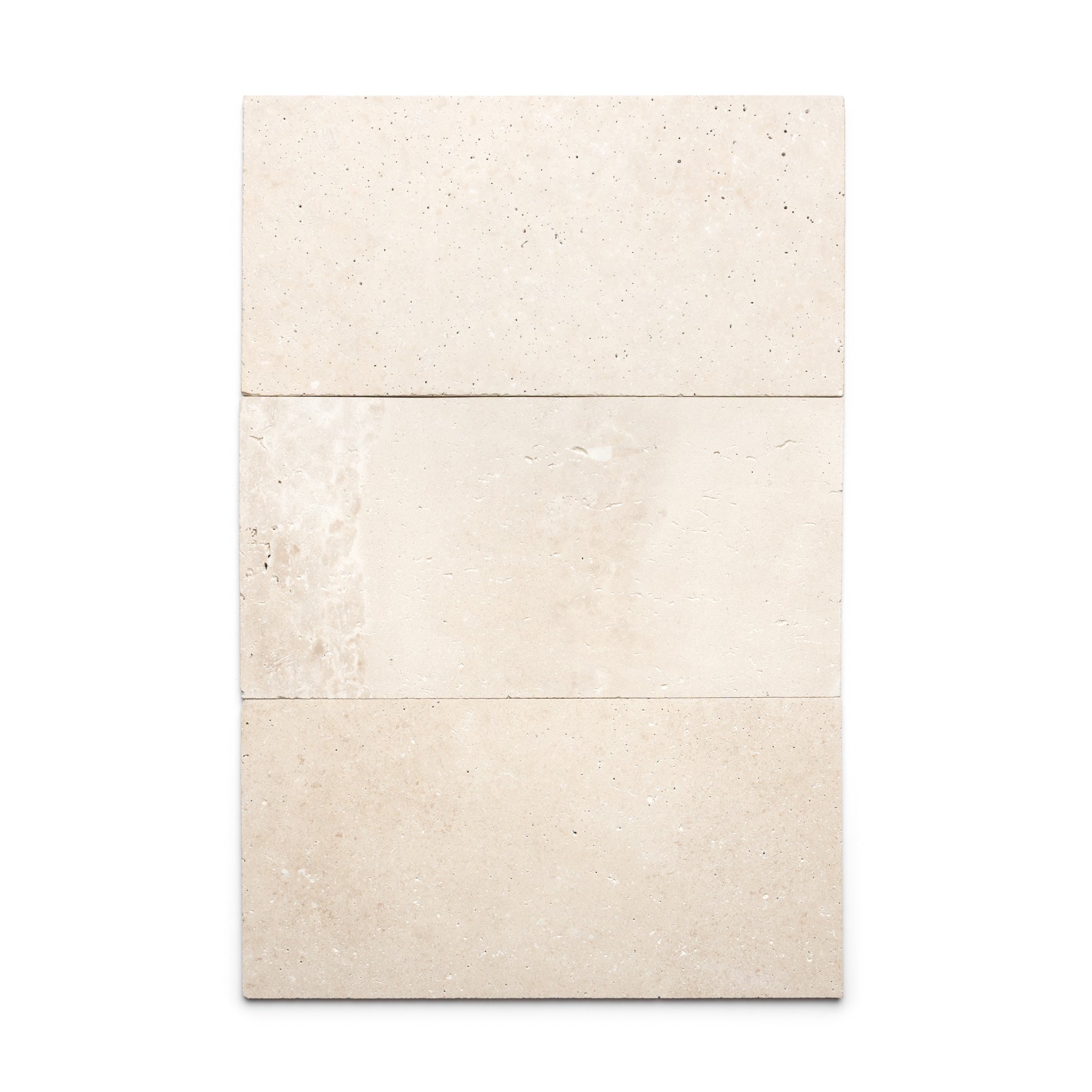Three rectangular Mesa 12x24 tiles by Zia Tile in beige Cantera stone are arranged vertically, with the middle tile showing a subtle texture and color variation. These Mexican tiles are displayed against a plain white background.