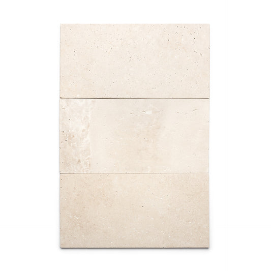 Three rectangular Mesa 12x24 tiles by Zia Tile in beige Cantera stone are arranged vertically, with the middle tile showing a subtle texture and color variation. These Mexican tiles are displayed against a plain white background.