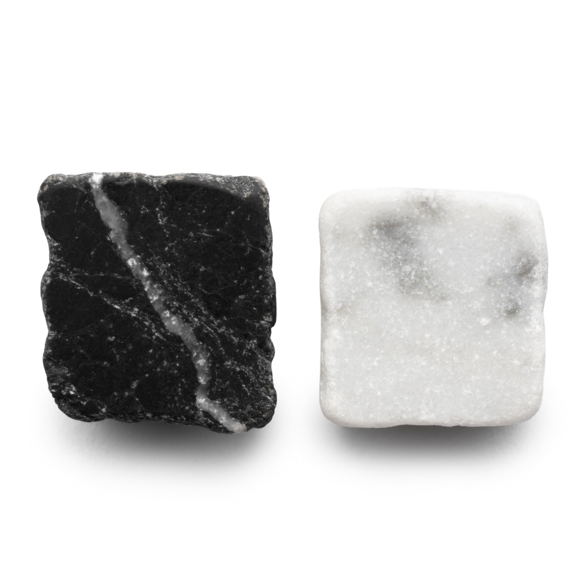 Mini Check in Carrara + Nero Marquina by Zia Tile: two square stones—one black with white veins and irregular edges, the other white with gray marbling and smooth, rounded edges—are displayed side by side on a white background.