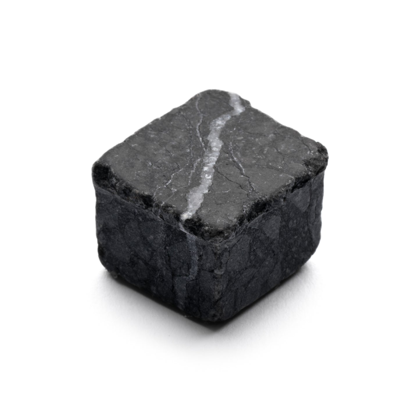 A single Mini Check in Carrara + Nero Marquina whiskey cube by Zia Tile, featuring dark gray stone with a white vein, placed on a white background.