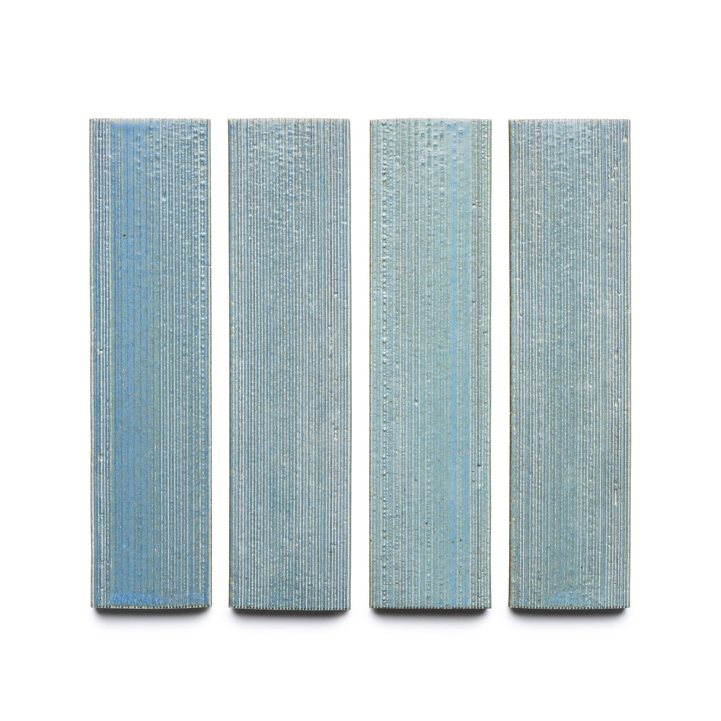 Four vertically oriented, rectangular Morning Light + Etched tiles by Zia Tile, in blue with a textured linear pattern, evenly spaced against a white background.
