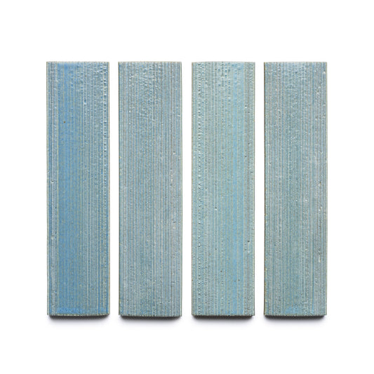 Four vertically oriented, rectangular Morning Light + Etched tiles by Zia Tile, in blue with a textured linear pattern, evenly spaced against a white background.