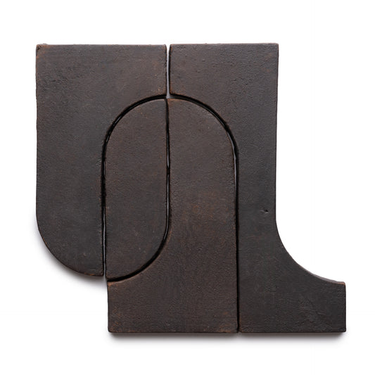 Four interlocking Durango + Oscura tiles by Zia Tile, in dark brown ceramic, feature smooth curves and straight edges forming an abstract, minimalist geometric shape on a white background.