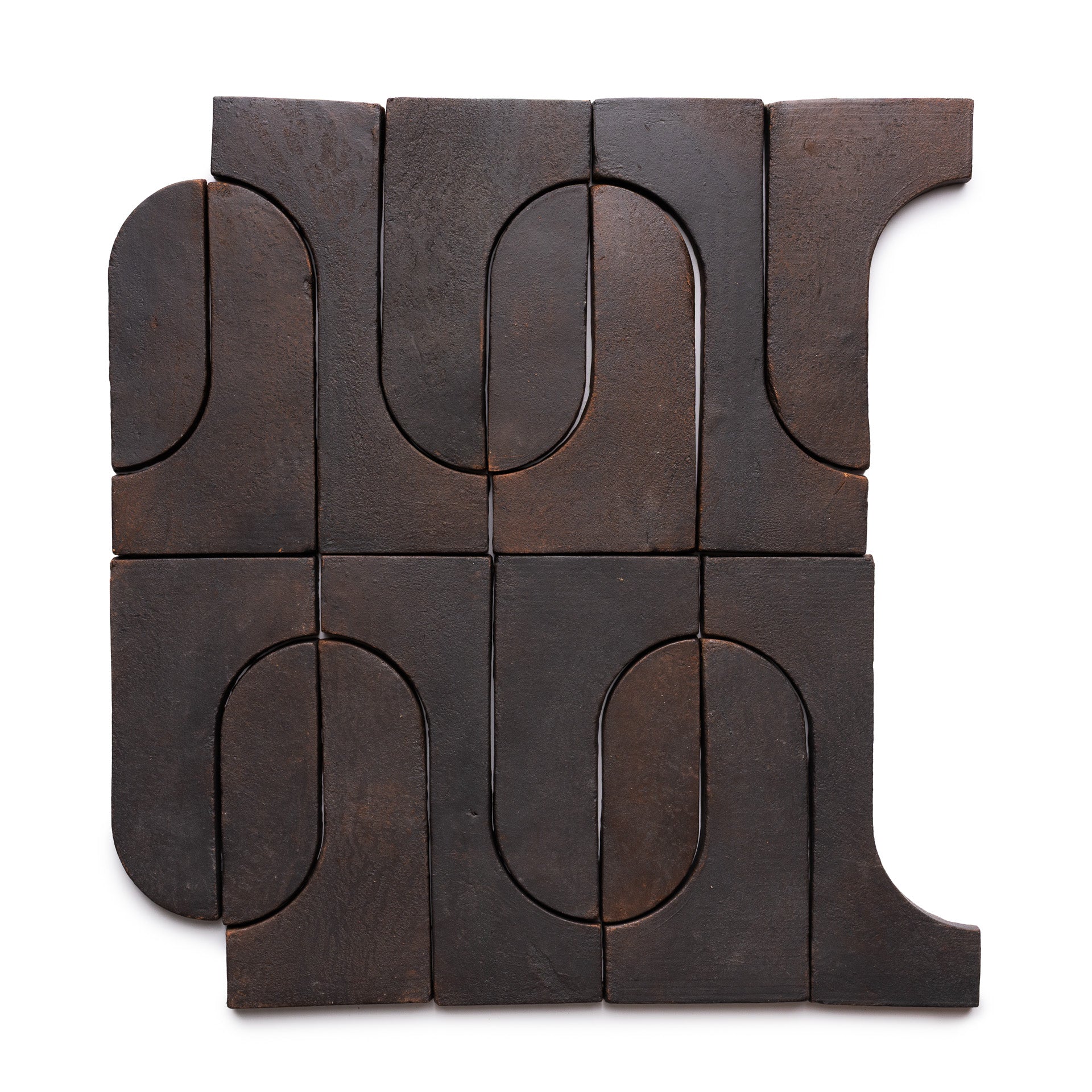 Twelve Durango + Oscura tiles from Zia Tile form a square, featuring dark brown ceramic with curved and straight indents that create an abstract, interlocking geometric pattern on a white background.