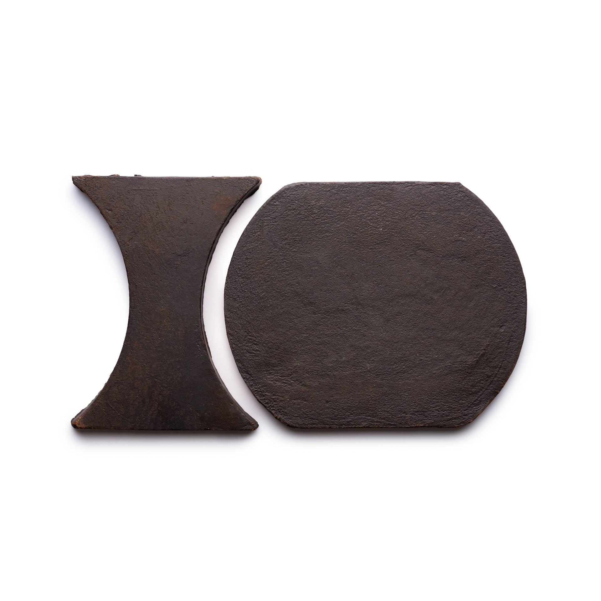 Oaxaca + Oscura by Zia Tile: two flat, dark metal tiles on a white background—one hourglass-shaped, the other a rounded rectangle with angled sides—displayed side by side.