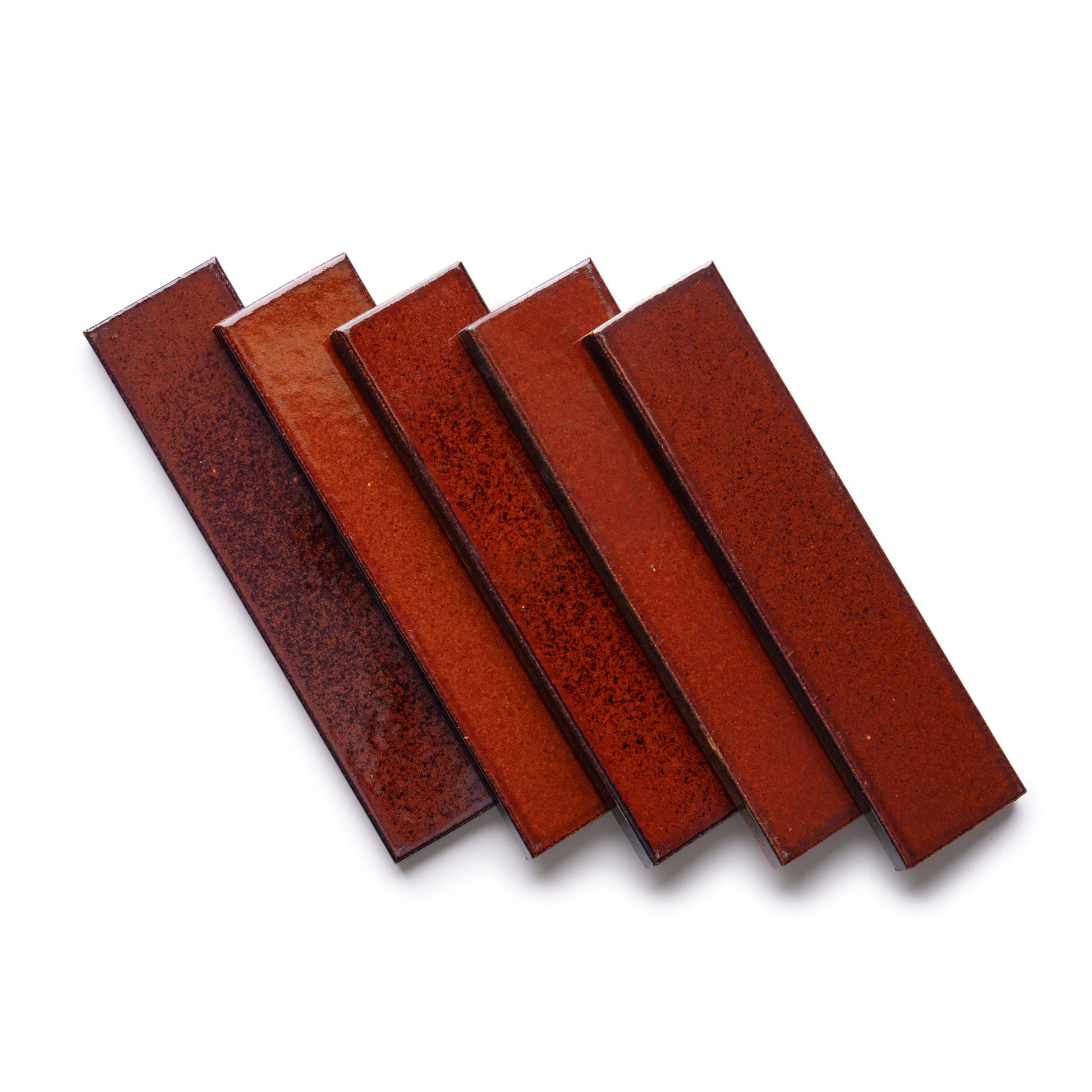 Five Oxblood + Flat tiles by Zia Tile, featuring a glossy, reddish-brown ceramic finish with subtle color variation, are arranged in a fanned-out pattern on a white background.