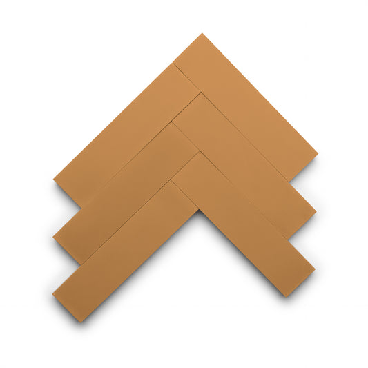 Four rectangular Saddle 2x8 tiles by Zia Tile are arranged in a herringbone pattern on a white background, forming an angled, geometric design.