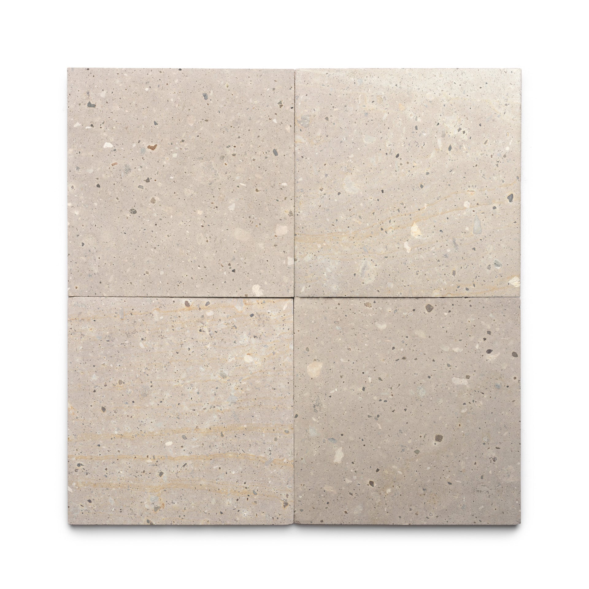 Four Sierra 12x12 tiles by Zia Tile, in square beige terrazzo with subtle speckles and natural stone variations inspired by Mexican Cantera stone, are arranged in a two-by-two grid on a white background.