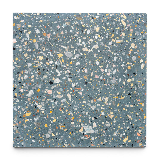 The Thunderbird 24x24 by Zia Tile is a handmade square cement terrazzo tile with a blue-gray base, featuring white, gray, yellow, and orange stone chips on a white background.