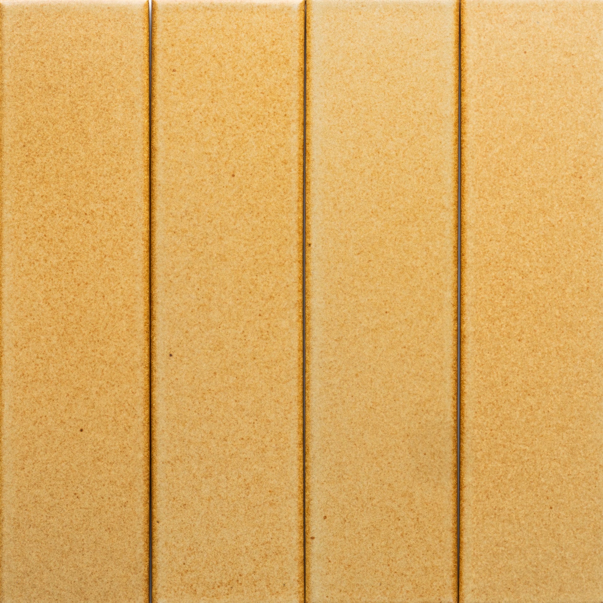 Four Toast + Flat tiles by Zia Tile are arranged vertically side by side, creating a seamless beige surface with narrow grout lines and a smooth, slightly speckled texture.