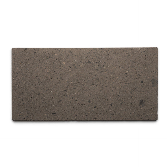 The Zia Tile Volcan 12x24 is a rectangular, flat brown tile made from natural volcanic stone with a smooth surface and subtle dark speckles, shown from above on a white background.