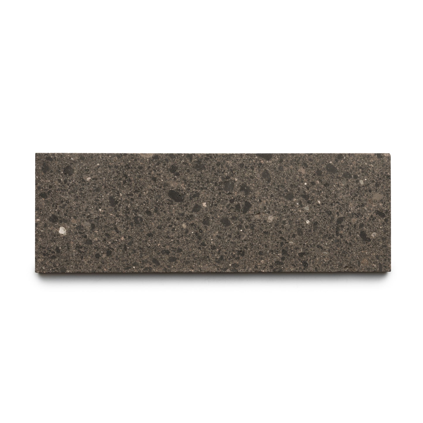 The Volcan 4x12 by Zia Tile is a rectangular dark gray, speckled tile featuring earth-toned aggregates and a smooth, stone-like surface, displayed against a white background.