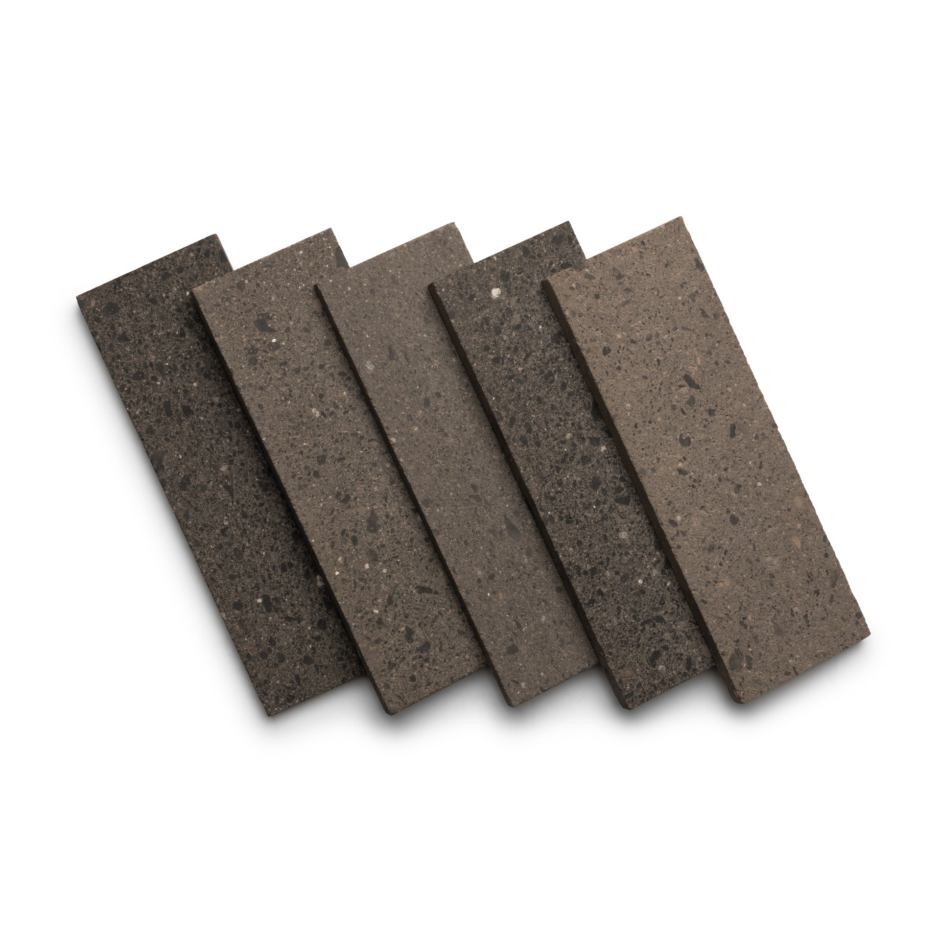 Five Zia Tile Volcan 4x12 rectangular tiles in earthy brown and gray tones are displayed fanned out on a white background. Each tile shows a speckled, textured surface characteristic of the collection.